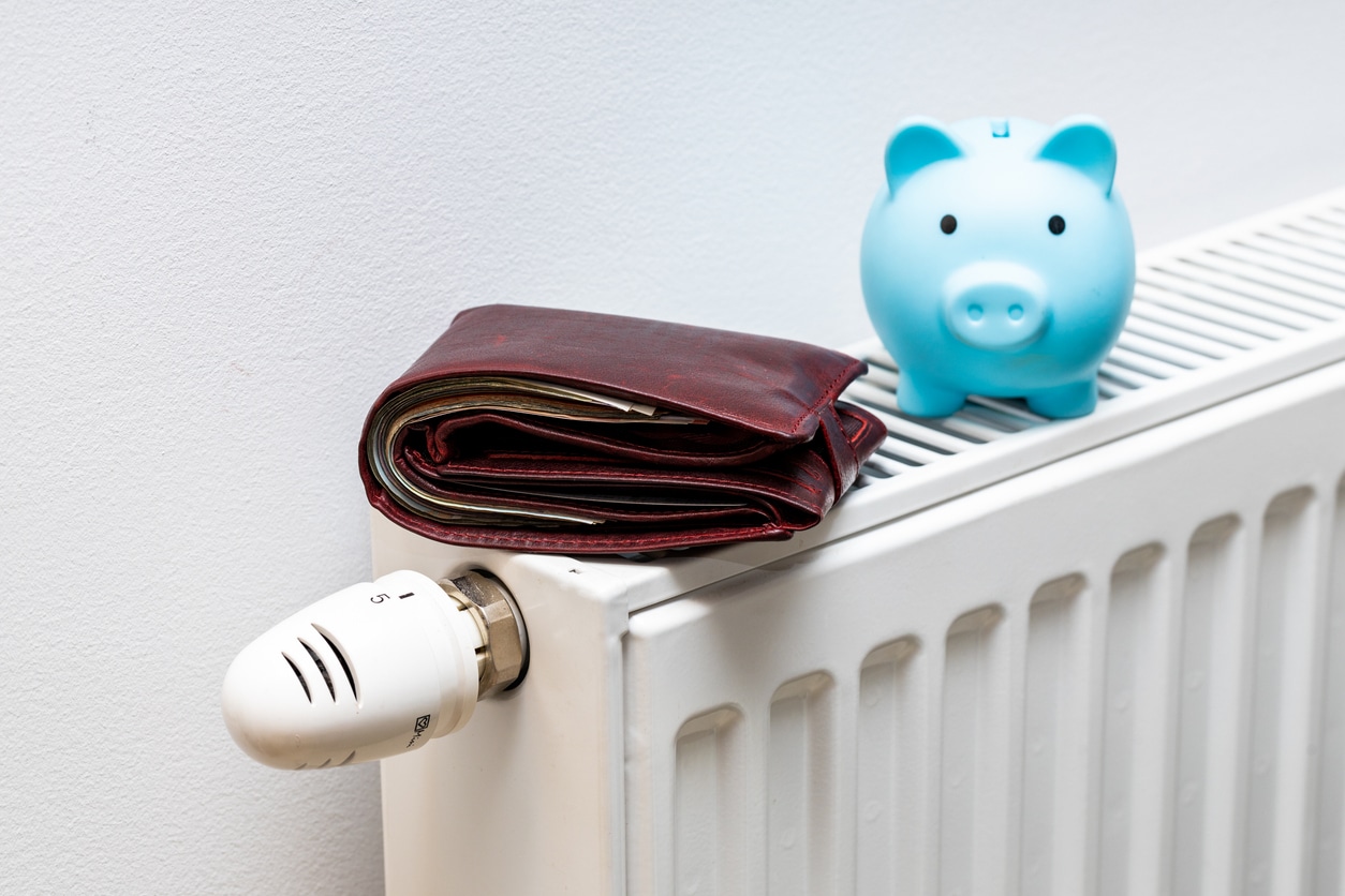 A radiator with a brown leather wallet and a bright blue piggy bank resting on top.