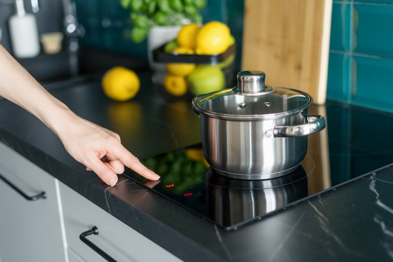 A cropped photo of a woman pressing on button on a newly converted electric induction stove.