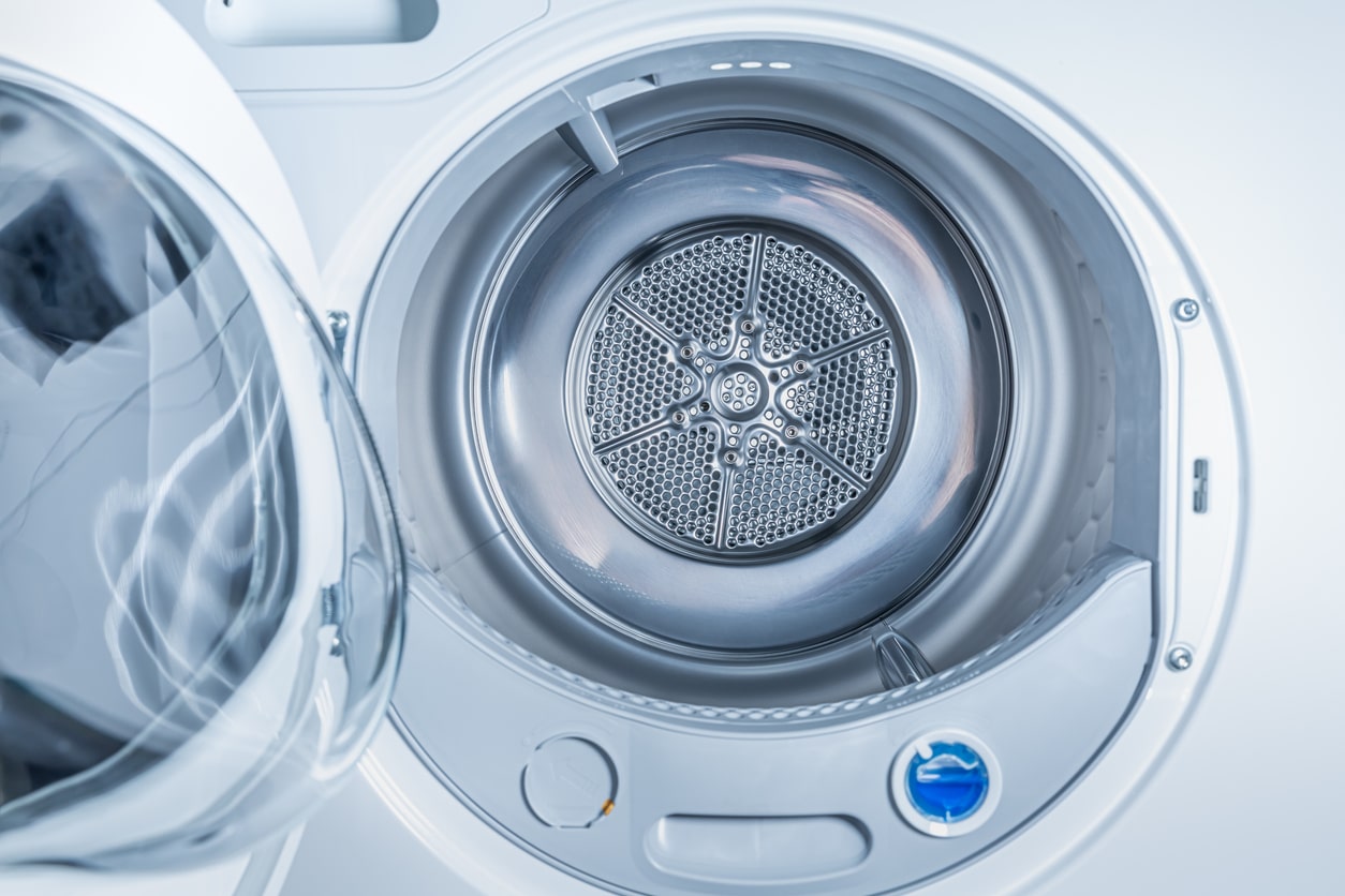 A close-up view of the inside of a heat pump clothes dryer. The bottom is chrome, and the surrounding metal is white.