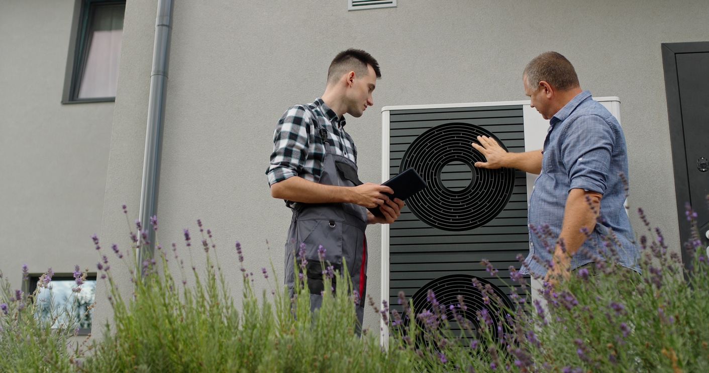 A professional HVAC technician showing a homeowner how their newly installed heat pump works.